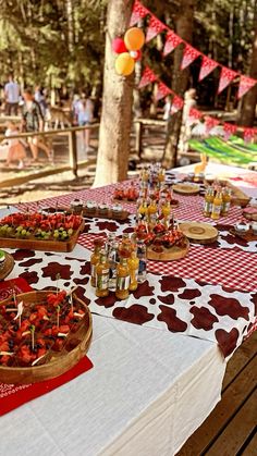 a picnic table with food and drinks on it in the woods for an outdoor party