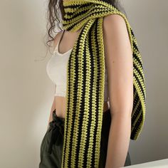 a woman wearing a green and black crocheted scarf with stripes on the ends