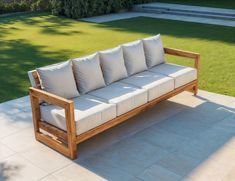 a wooden couch sitting on top of a cement floor next to a lush green field