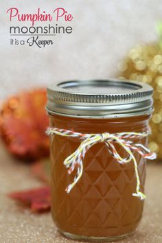 a mason jar filled with liquid sitting on top of a table next to autumn leaves