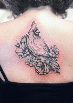 the back of a woman's shoulder with a bird and flowers tattoo on it