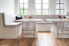 a kitchen with two white benches and some flowers in vases on the windowsill