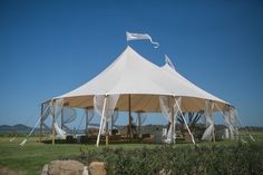 a large white tent sitting on top of a lush green field