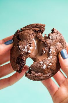 a person holding a chocolate doughnut with icing in their hands, on a blue background