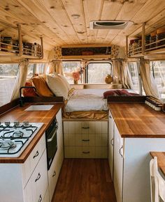 the interior of a camper with wood flooring and white walls, including an open kitchen area