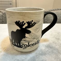 a coffee cup with moose silhouettes on it sitting on top of a white table