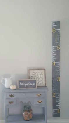 a blue table with a ruler on the wall next to it and a vase filled with flowers