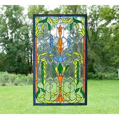 a stained glass window in the shape of a vase on a lawn with trees behind it