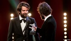 two men standing next to each other in front of microphones at an awards ceremony