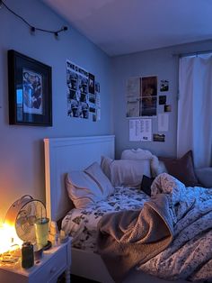 an unmade bed in a room with posters on the wall and a fan next to it