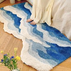 a woman sitting on the floor in front of a blue and white rug with waves