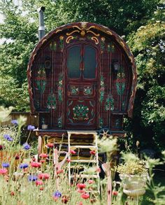 an elaborately decorated horse drawn carriage in the middle of a field full of wildflowers