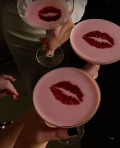 three people holding wine glasses with red liquid in them and the lips painted on them