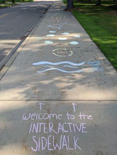 the sidewalk has chalk writing on it that says, welcome to the interactive side walk