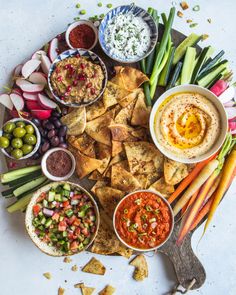 a platter filled with dips, crackers and vegetables