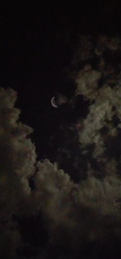 the moon is seen through some clouds at night