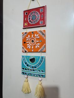 three colorful wall hangings with tassels on them