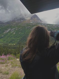 a woman is looking at the mountains with binoculars