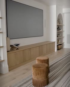 a living room with two stools and a large screen