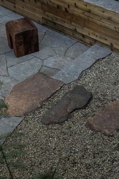 a bench sitting on top of a gravel covered ground next to a wooden fence and planter