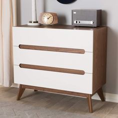 a white dresser with three drawers and a hat on top