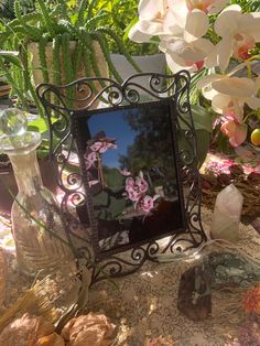 a mirror sitting on top of a table next to flowers