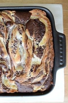 a loaf of bread sitting on top of a white and black pan covered in chocolate