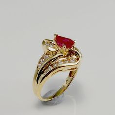 a gold ring with a red stone surrounded by diamonds