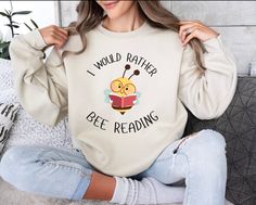 "Buzz with excitement over our 'I WOULD RATHER BEE READING' crewneck sweatshirt from AnnGeeGifts! 🐝 Perfect for teachers who love to inspire a love for books in their students. Crafted for comfort and style, this cozy sweatshirt is a must-have addition to any educator's wardrobe. Whether you're cozying up with a book or leading a class discussion, let your passion for reading shine. Spread the buzz and grab yours today!" .: Made with a medium-heavy fabric blend of 50% cotton and 50% polyester ( Librarian Shirt, Gift For Book Lover, Gifts For Librarians, Book Shirts, Cozy Sweatshirts, Shopping Spree, Mind Blowing, Book Lovers Gifts, Book Lover