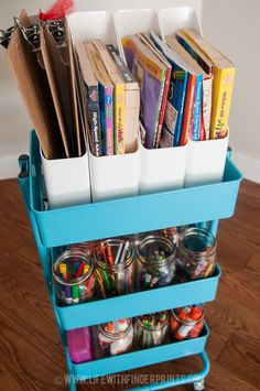 a blue cart filled with lots of books on top of a hard wood floor