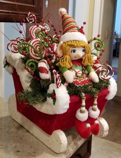 a christmas decoration with candy canes and a doll sitting in it's sleigh