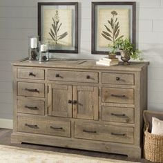 an old dresser with two framed pictures above it