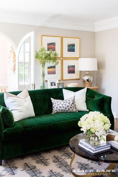 a living room filled with green couches and white flowers on top of a coffee table