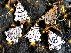 three decorated christmas tree ornaments hanging from string on top of a black surface with lights