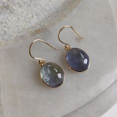 ITEM DESCRIPTION: >> The earrings are made from Solid 14K Yellow Gold. Gemstone used is absolutely natural and ethically sourced. >> Naturally occurring Bi-color Tanzanite Cabochon with shades of blue and green in bezel setting is studded on it with utmost precision. >> This is a minimalist design and is absolutely hassle-free and everyday jewelry. Gem: Bi-color Tanzanite Gem size: 10x12 mm Gem weight: 12.22 carats Gold purity: 14K (58.33% approx.) Gold weight: 0.70 grams Gross weight: 3.14 gram Round Tanzanite Earrings Gift, Tanzanite Round Earrings As Gifts, Round Tanzanite Earrings For Gifts, Oval Tanzanite Gemstone Earrings, Yellow Gold Tanzanite Jewelry With Matching Earrings, Tanzanite Teardrop Earrings As A Gift, Tanzanite Birthstone Earrings As Gift, Tanzanite Birthstone Earrings For Gifts, Tanzanite Jewelry Set With Matching Earrings As Gift