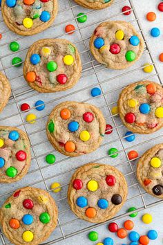 cookies with m & m's and chocolate chips on a cooling rack surrounded by candy