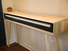 a piano sitting on top of a wooden table next to a plant in a pot