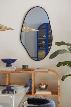 a mirror hanging on the wall next to a table with a chair and plant in it