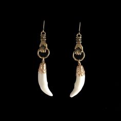 a pair of earrings with white and gold colored beads on them, hanging from hooks