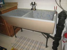 a kitchen sink sitting under a faucet on top of a tiled countertop