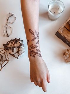 a person with a tattoo on their arm next to some candles and other items that are sitting on a table