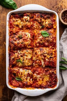 a casserole dish with meat, cheese and spinach leaves on the side