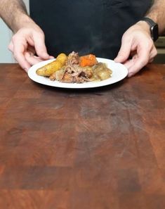 a man holding a plate with food on it sitting at a table in front of him