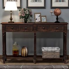 a wooden table with two drawers and three pictures on the wall above it in a living room