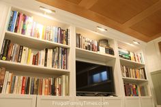 a bookshelf filled with lots of books next to a flat screen tv on top of a wooden ceiling