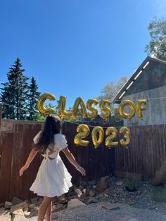 a woman in a white dress standing next to a fence with the words class of 202