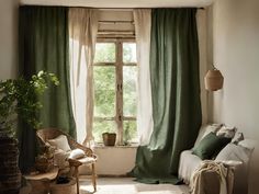 a living room filled with furniture and green drapes on the windowsill, next to a potted plant