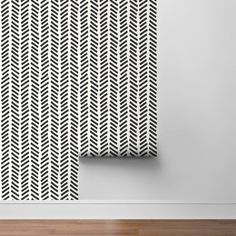 two black and white wallpapers in an empty room with wood flooring on the side