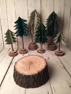 several cut out trees sitting next to each other on a white wooden surface with one tree stump in the foreground