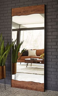 a mirror sitting on top of a brick wall next to a potted green plant